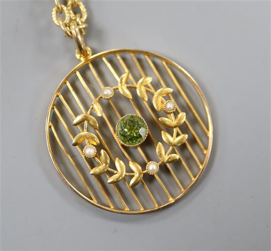 An early 20th century 9ct, peridot and seed pearl set openwork pendant on a gilt metal chain, pendant 29mm.